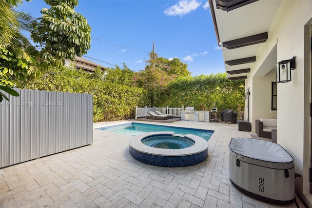 view of swimming pool featuring a patio area, area for grilling, fence, and a pool with connected hot tub