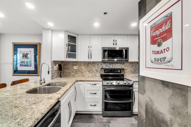 kitchen with a sink, white cabinetry, appliances with stainless steel finishes, and light stone countertops