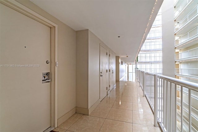 corridor featuring baseboards and light tile patterned floors
