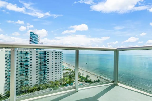 balcony with a water view and a view of the beach