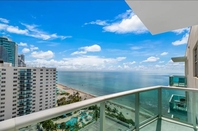 balcony with a water view and a view of the beach