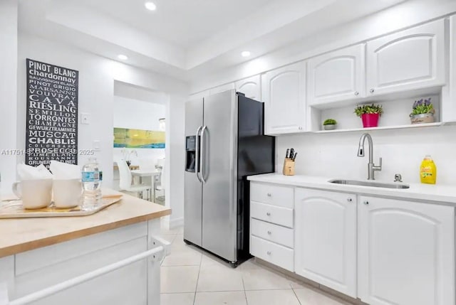 kitchen featuring stainless steel fridge, white cabinets, light countertops, open shelves, and a sink