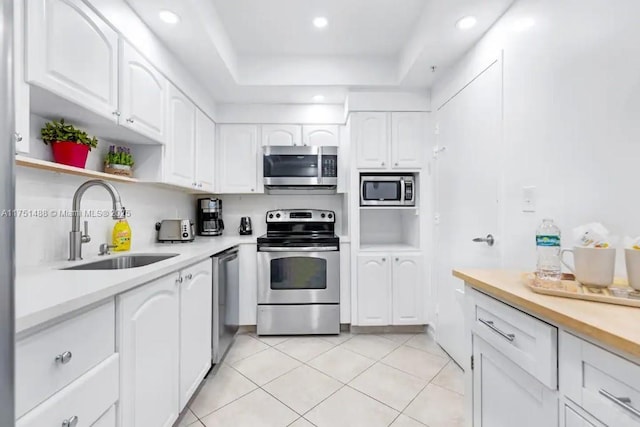 kitchen featuring appliances with stainless steel finishes, light countertops, a sink, and white cabinetry