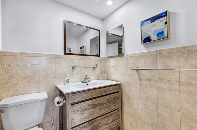 bathroom featuring toilet, wainscoting, tile walls, and vanity