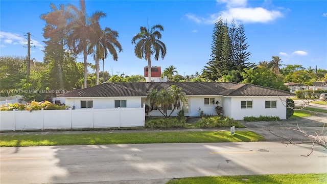 view of front of property featuring a tile roof, a chimney, fence, and stucco siding