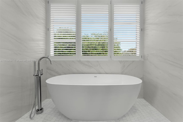 bathroom featuring a soaking tub, tile walls, and a healthy amount of sunlight