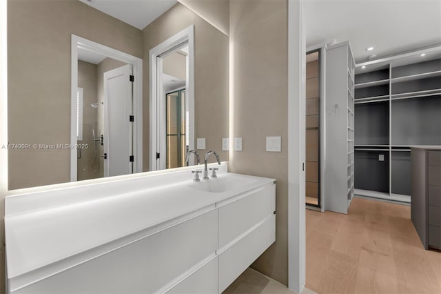 bathroom featuring an enclosed shower, wood finished floors, vanity, and recessed lighting