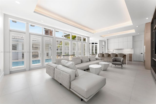 living room with light tile patterned floors, a raised ceiling, a wealth of natural light, and recessed lighting