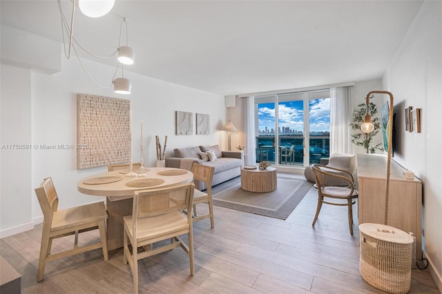 dining space with light wood finished floors, a wall of windows, and baseboards