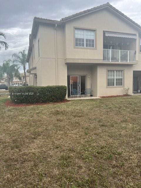 back of property featuring a lawn and stucco siding