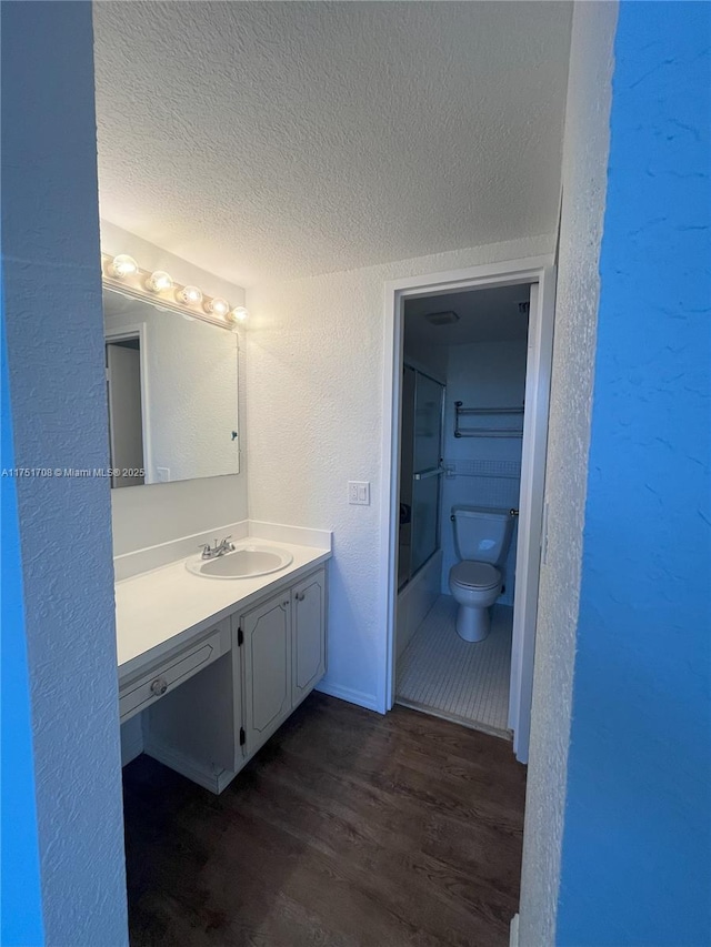 3660 NE 166th St Unit 305, North Miami Beach, FL 33160 - full bath with a textured wall, toilet, vanity, a textured ceiling, and wood finished floors