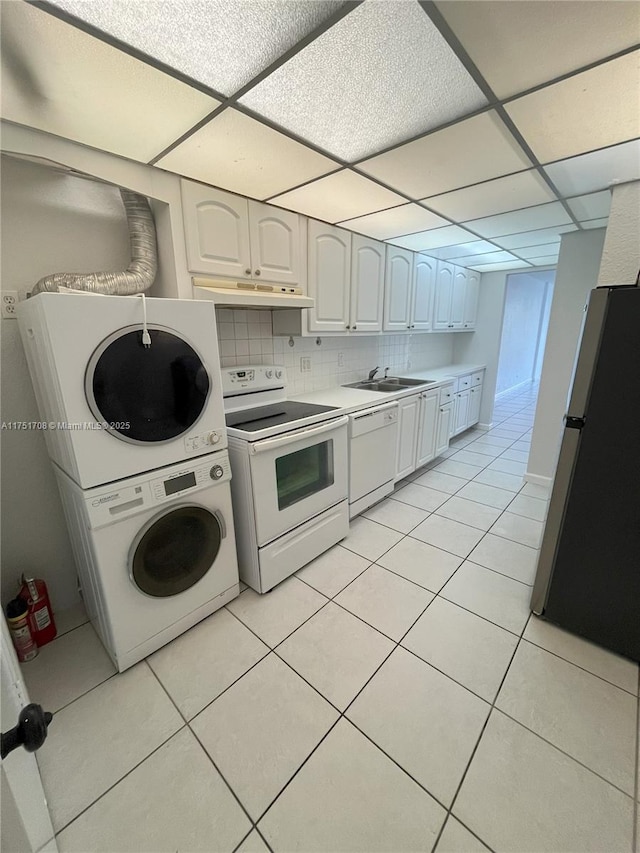3660 NE 166th St Unit 305, North Miami Beach, FL 33160 - kitchen with white appliances, stacked washing machine and dryer, a paneled ceiling, light tile patterned floors, and light countertops