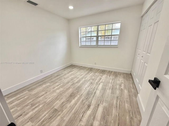 unfurnished bedroom with light wood-style flooring, a closet, visible vents, and baseboards