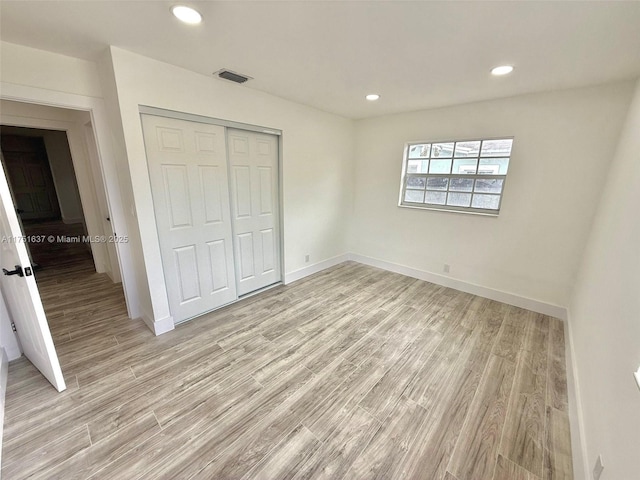 unfurnished bedroom with light wood-type flooring, a closet, baseboards, and recessed lighting