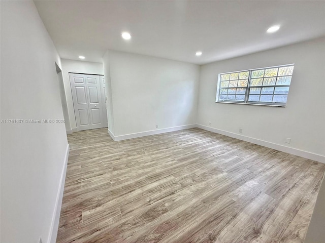 spare room featuring recessed lighting, light wood-type flooring, and baseboards