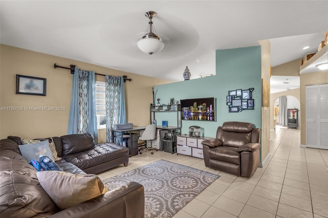 living area featuring light tile patterned floors, arched walkways, and vaulted ceiling