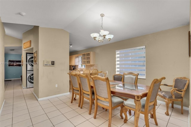 dining area featuring lofted ceiling, stacked washer and clothes dryer, light tile patterned floors, and an inviting chandelier