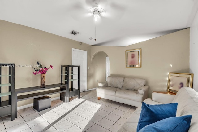 living room featuring light tile patterned floors, baseboards, visible vents, and arched walkways