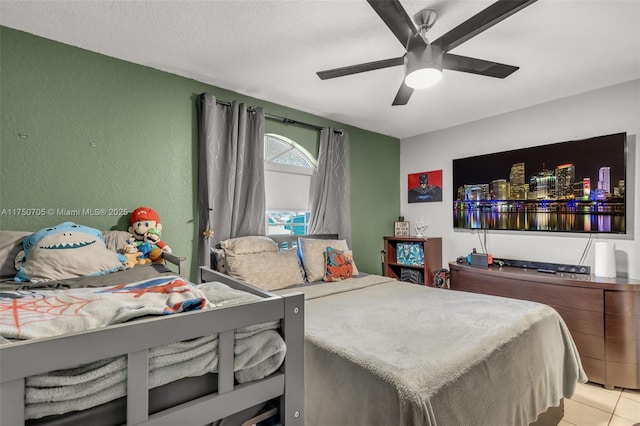 bedroom with ceiling fan, a textured wall, a textured ceiling, and tile patterned floors