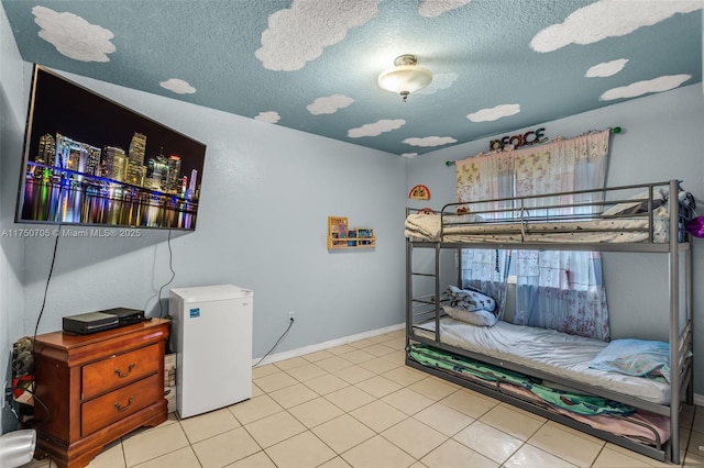 bedroom with refrigerator, light tile patterned flooring, a textured ceiling, and baseboards