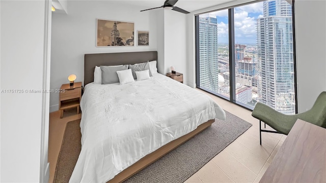 bedroom featuring tile patterned flooring, expansive windows, a ceiling fan, access to exterior, and a view of city