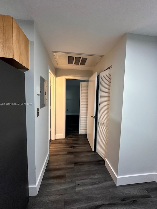 corridor featuring electric panel, dark wood finished floors, visible vents, and baseboards