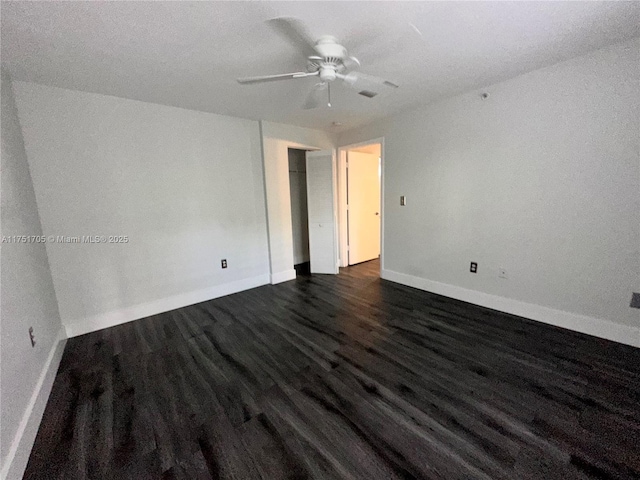 spare room with dark wood-type flooring, ceiling fan, and baseboards