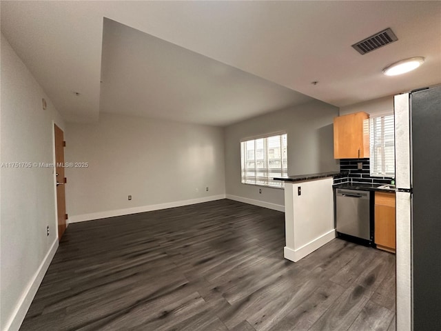 kitchen featuring a peninsula, dark wood-style flooring, visible vents, appliances with stainless steel finishes, and dark countertops