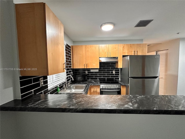 kitchen featuring wall oven, visible vents, freestanding refrigerator, under cabinet range hood, and a sink