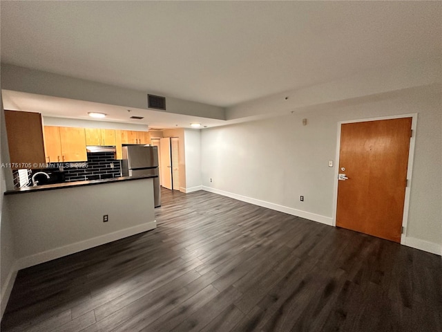 unfurnished living room with baseboards, visible vents, dark wood finished floors, and a sink