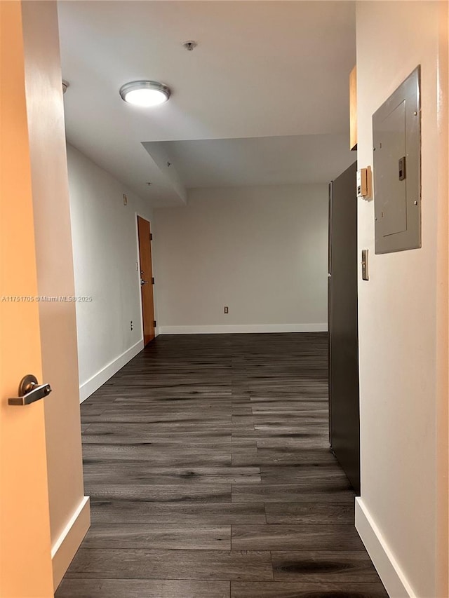 unfurnished room featuring dark wood-style flooring, electric panel, and baseboards