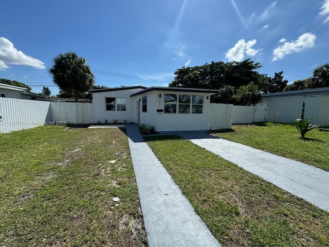 view of front of home with stucco siding, fence, and a front yard