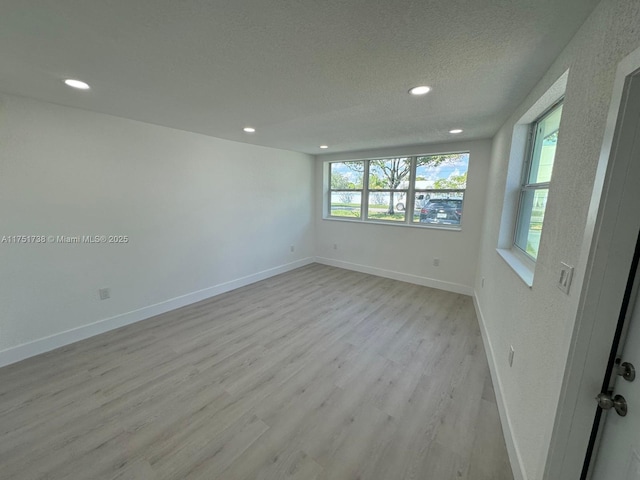 unfurnished room featuring recessed lighting, a textured ceiling, baseboards, and light wood-type flooring