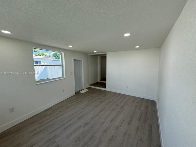 empty room with baseboards, wood finished floors, recessed lighting, and a textured ceiling