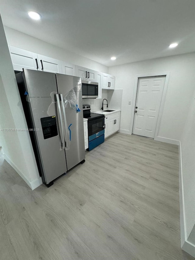 kitchen featuring light wood finished floors, a sink, light countertops, and appliances with stainless steel finishes