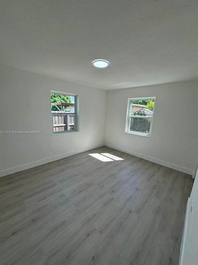 spare room featuring baseboards, a wealth of natural light, and wood finished floors