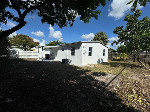 rear view of house with a fenced backyard, cooling unit, and stucco siding