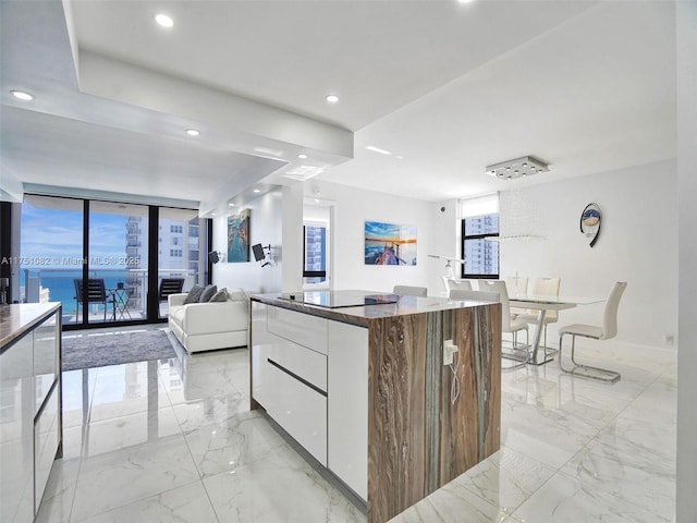 kitchen with marble finish floor, modern cabinets, a kitchen island, and white cabinets