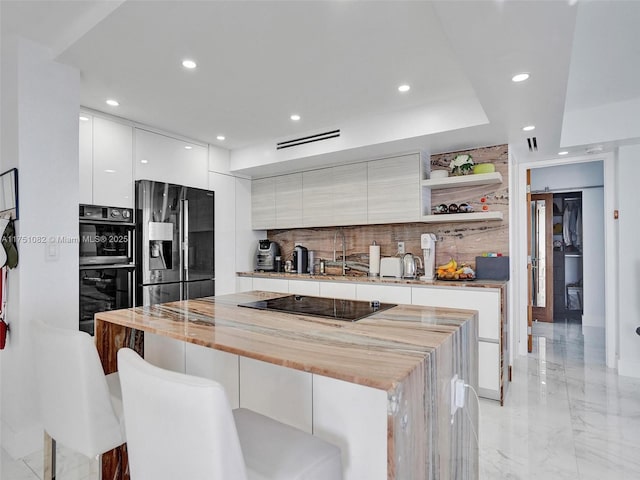 kitchen featuring open shelves, fridge with ice dispenser, modern cabinets, and a breakfast bar