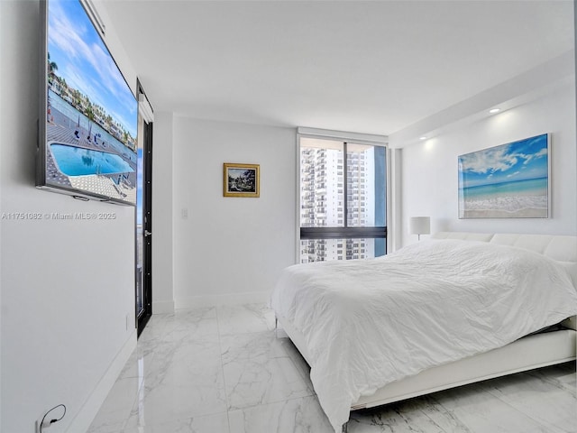 bedroom with marble finish floor, a city view, and baseboards