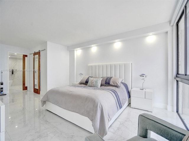 bedroom featuring marble finish floor, ensuite bathroom, and a barn door