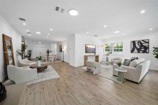 living area with baseboards, light wood-type flooring, visible vents, and recessed lighting