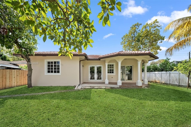 back of house with french doors, a lawn, a tile roof, and a fenced backyard