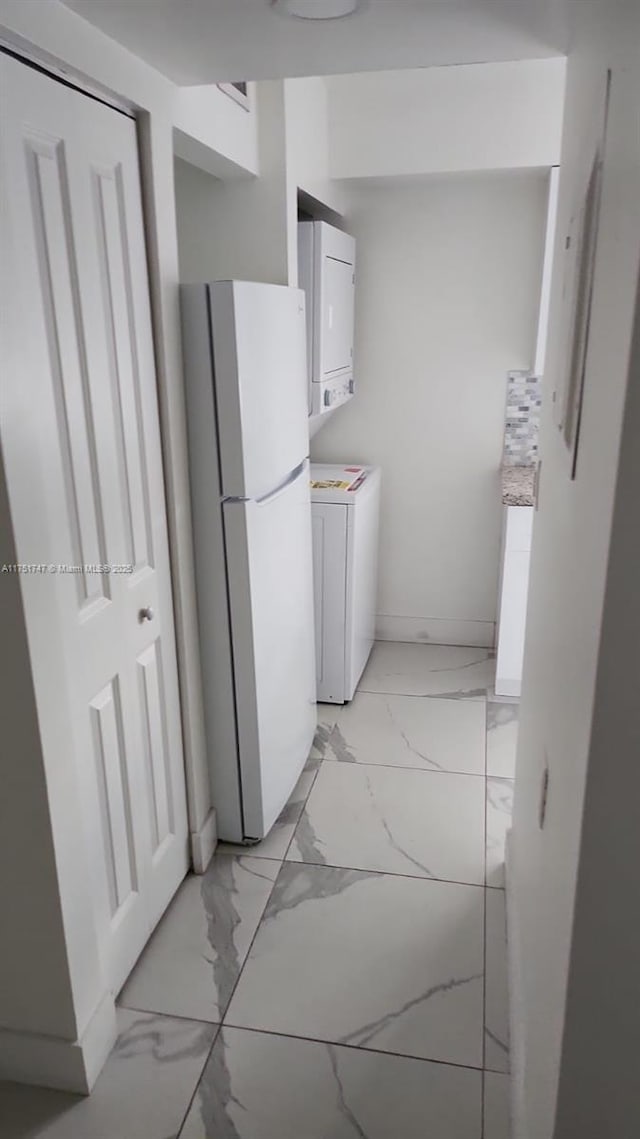 clothes washing area with stacked washer / drying machine, marble finish floor, and laundry area