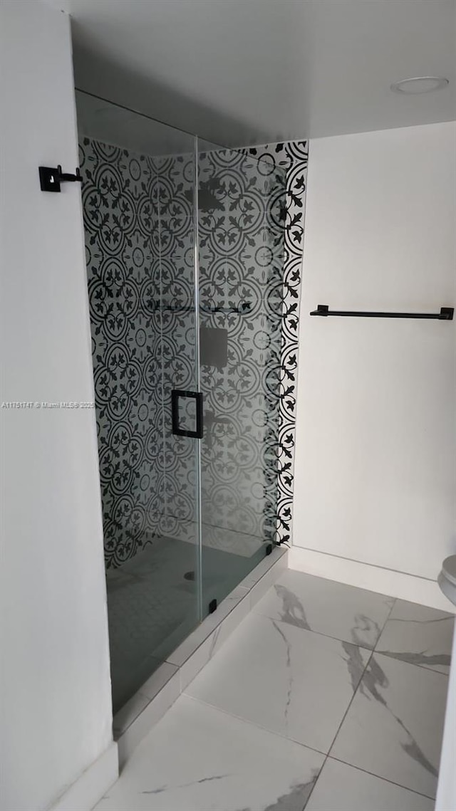 bathroom featuring marble finish floor and a shower stall