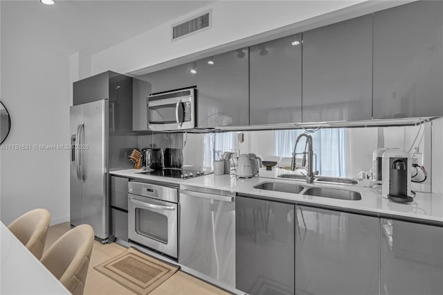 kitchen featuring stainless steel appliances, light countertops, visible vents, a sink, and modern cabinets