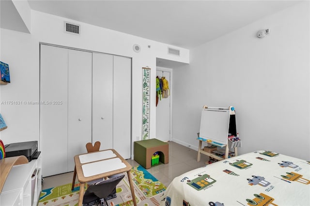 bedroom with light tile patterned floors, a closet, visible vents, and refrigerator