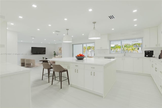 kitchen featuring pendant lighting, a spacious island, open floor plan, and white cabinets