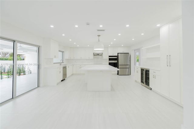 kitchen featuring stainless steel appliances, a kitchen island, white cabinetry, light countertops, and pendant lighting