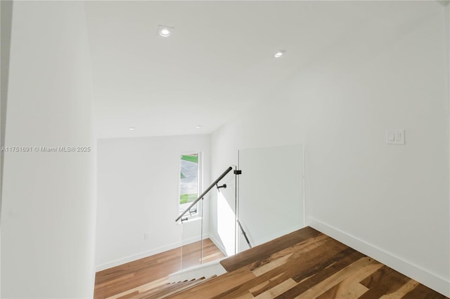 corridor featuring recessed lighting, baseboards, an upstairs landing, and wood finished floors